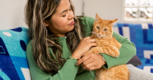 Woman with long brown hair holding an orange cat
